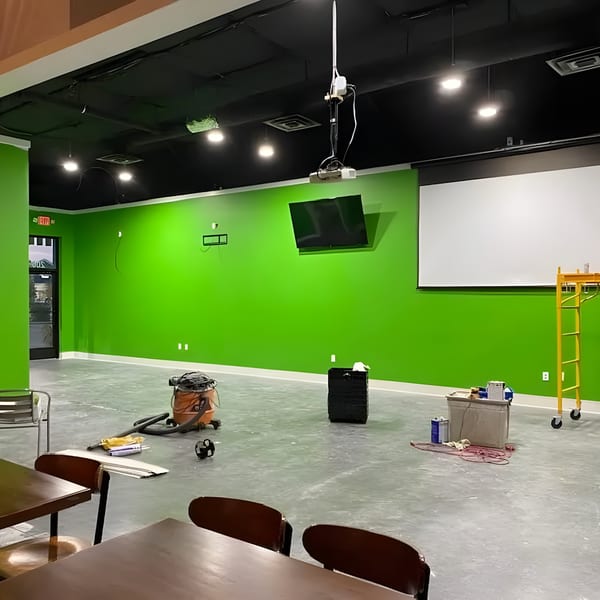 Unfinished Green Fire Pizza interior with bright green walls, concrete floor, and construction equipment.
