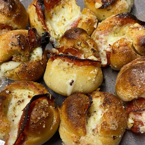Close-up of Green Fire Pizza's pepperoni and cheese pizza knots, golden brown with melted cheese.